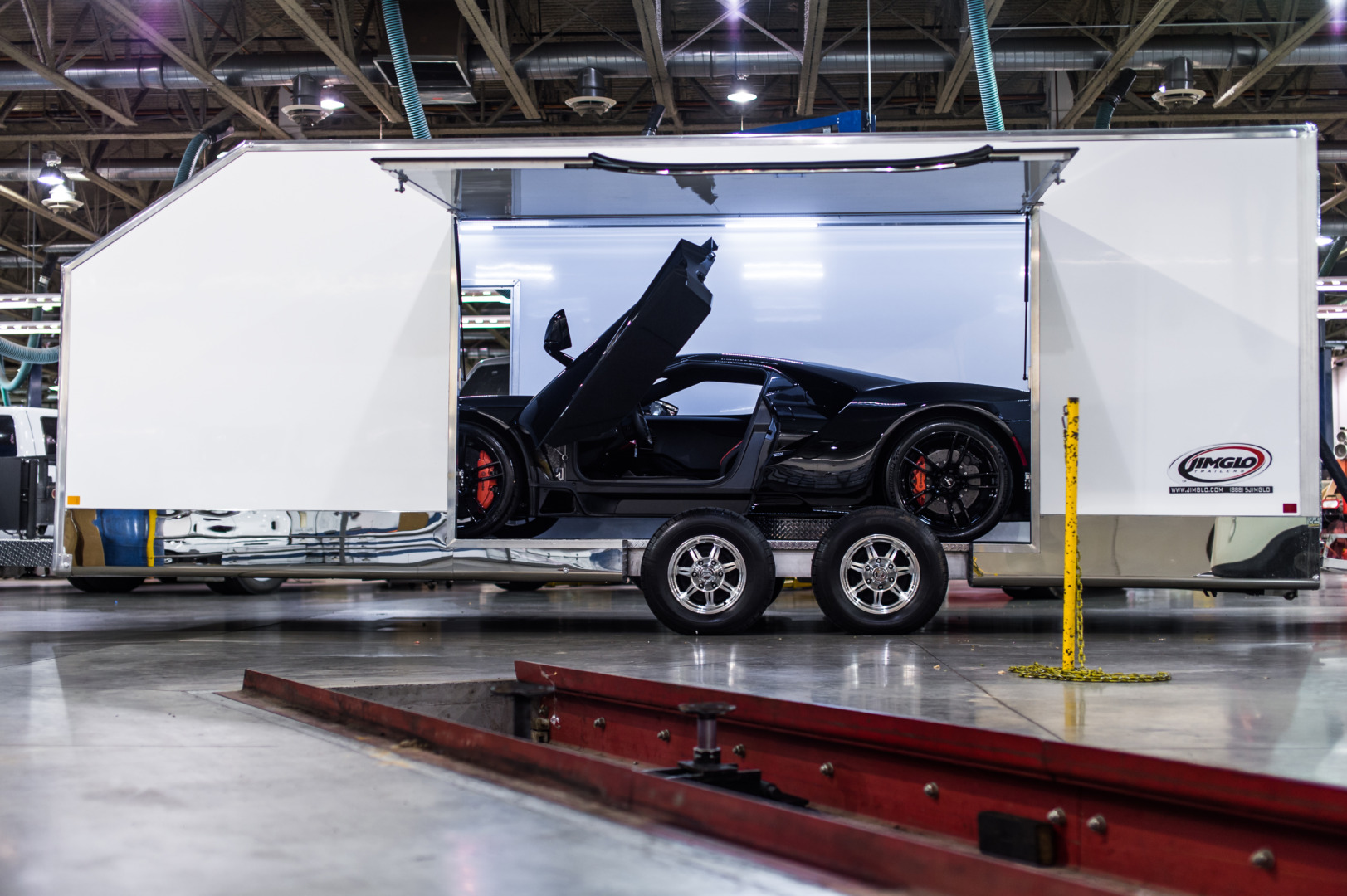 black ford gt inside jimglo elite enclosed car trailer with driver door open and trailer escape door open.