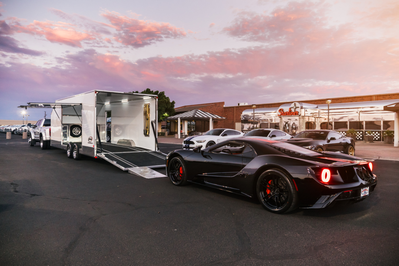a black sports car parked next to a white jimglo trailer